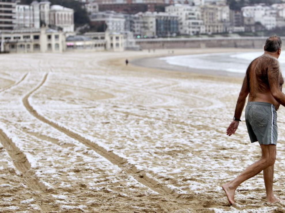 Un hombre se mete al agua en la playa de la Concha de San Sebastián