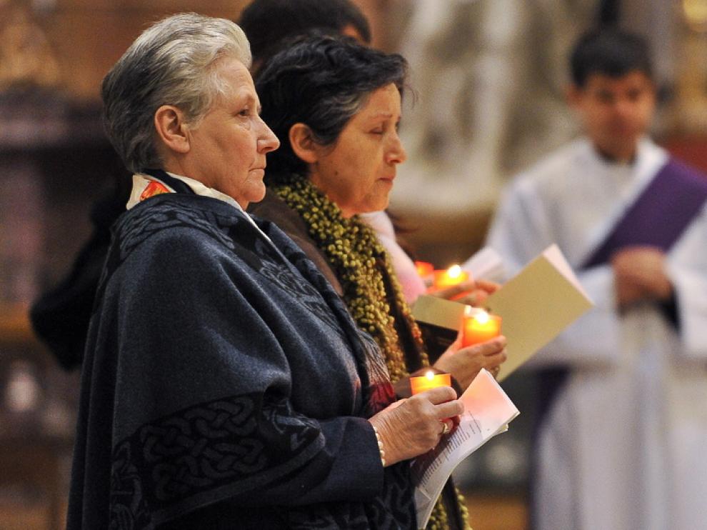 Marie Callins (i) sostiene una vela durante el acto.