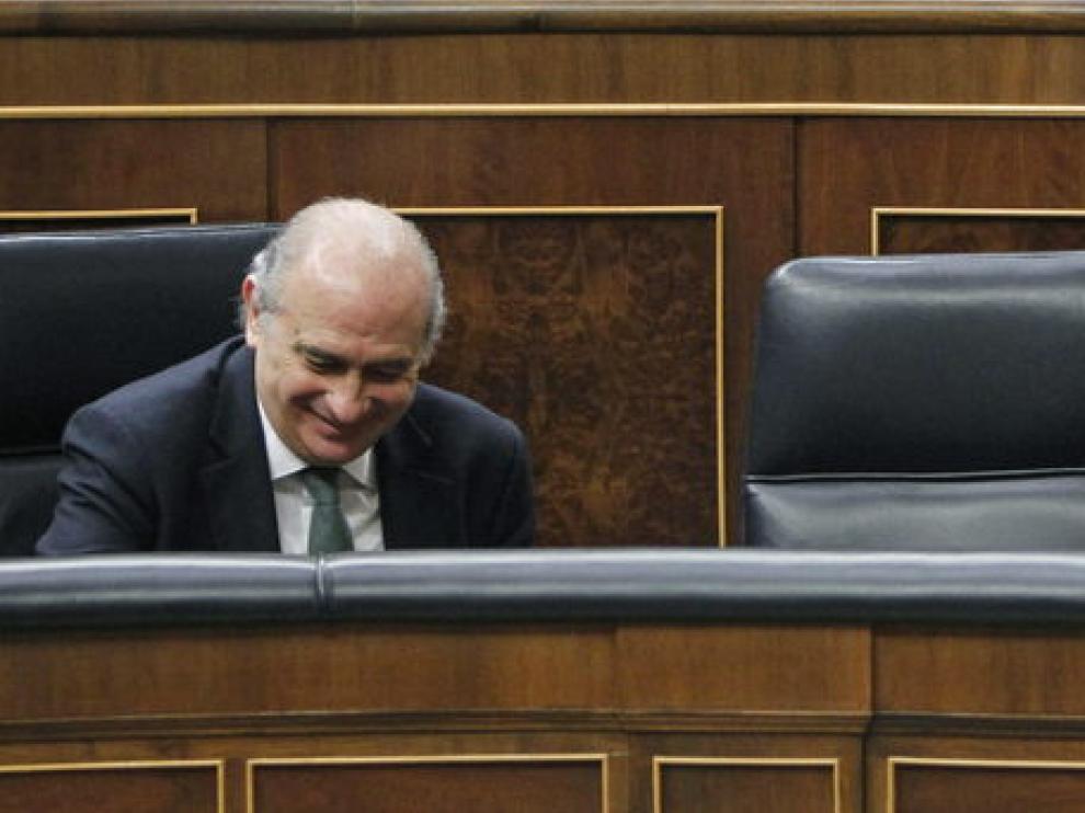 El ministro del Interior (i) y el de Justicia (d) sonríen en sus escaños durante el Pleno.
