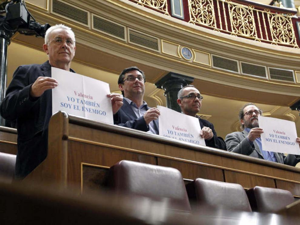 El diputado de IU, Cayo Lara, sotiene en el Congreso una pancarta que dice "Yo también soy el enemigo"