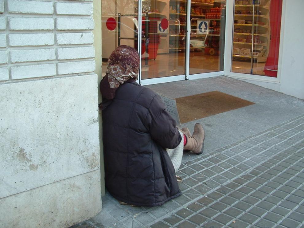 Una mujer pide limosna en la puerta de un supermercado de Huesca