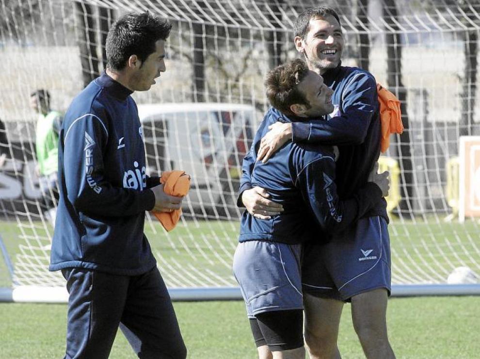 Josetxo se abraza con Llamas ante la mirada de Jorge Larena durante el entrenamiento de ayer en el IES Pirámide.