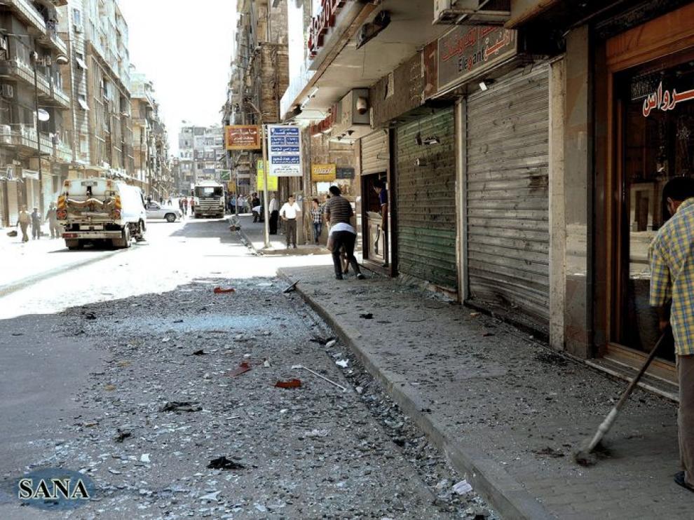 Un hombre limpia los escombros tras la explosión de una bomba en la ciudad de Aleppo.
