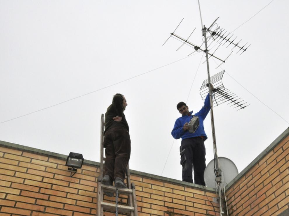 Unos técnicos ajustan la antena de televisión de una vivienda