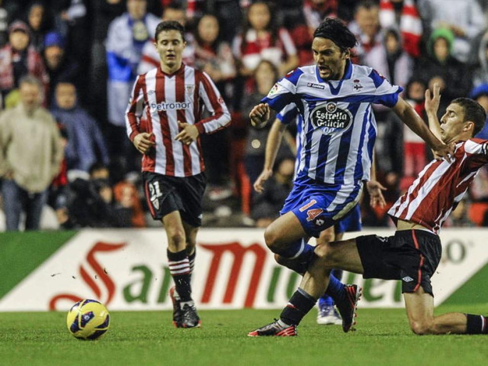 El delatentero del Athletic, Óscar de Marcos (d) lucha un balón con el centrocampista del DeporAbel Aguilar (c), durante el partido en San Mamés