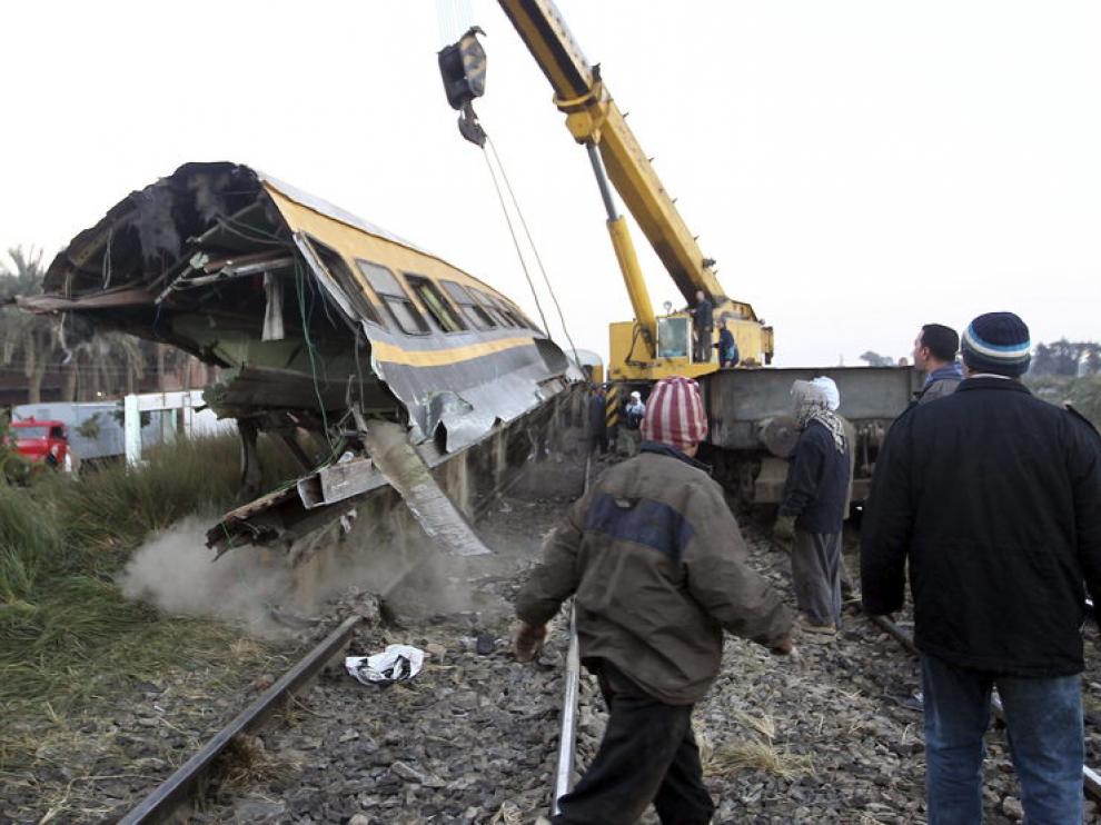 Miembros de los equipos de rescate levantan un vagón de tren tras un accidente en Guiza.
