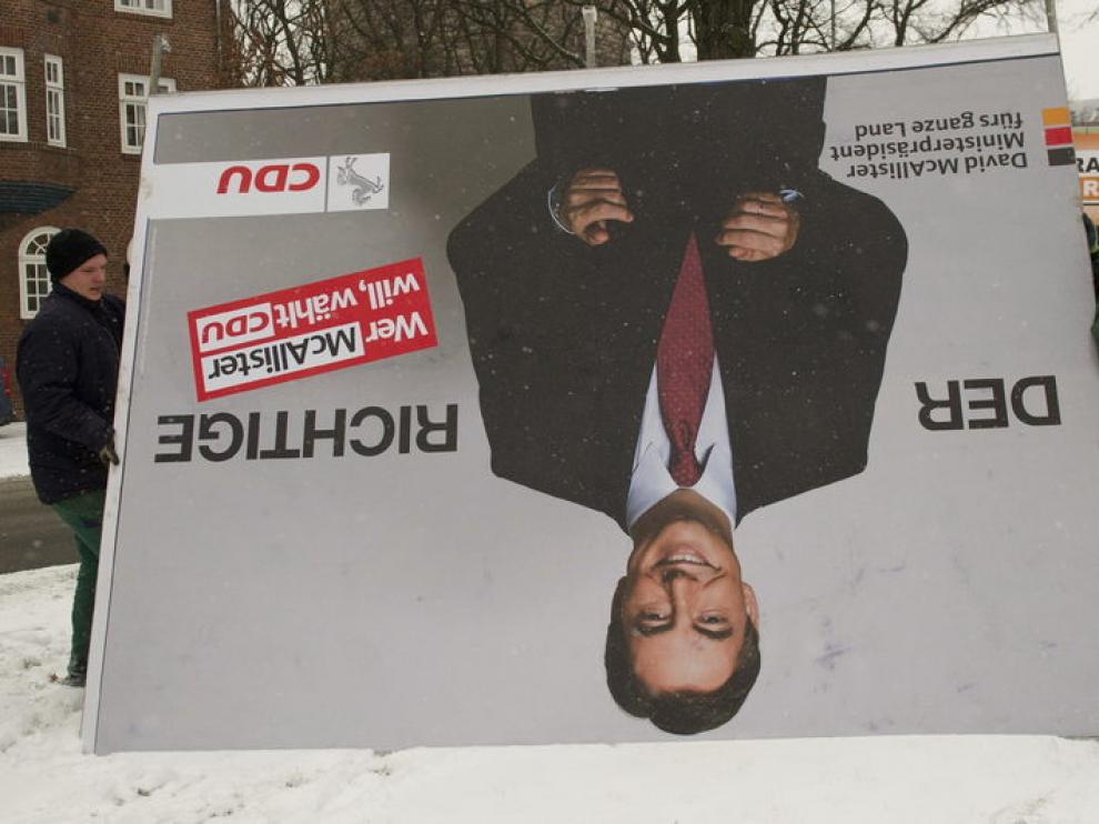 Dos operarios retiran el cartel del candidato de la CDU