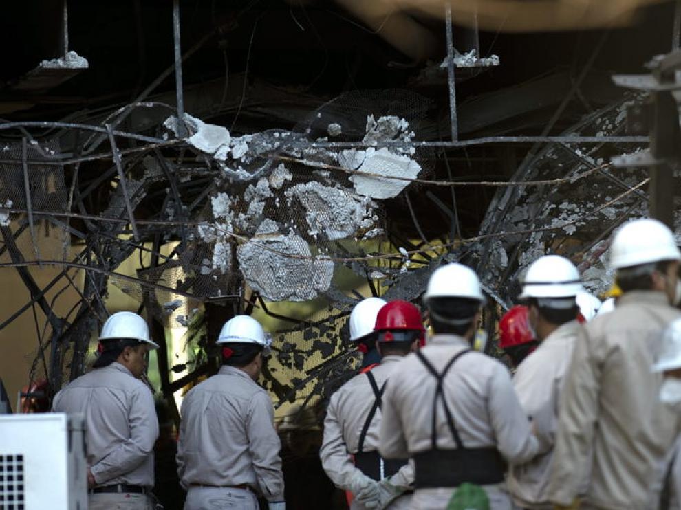 Empleados de Pemex observan los daños causados por la explosión