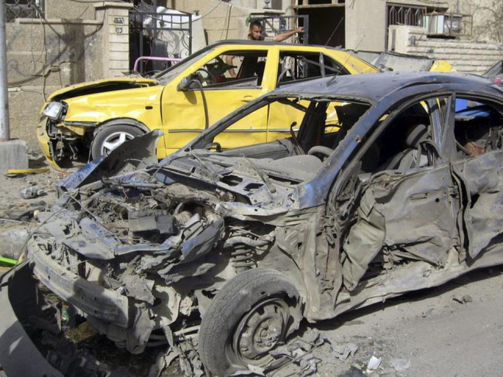 Dos hombres inspeccionan los coches dañados tras la explosión en Bagdad