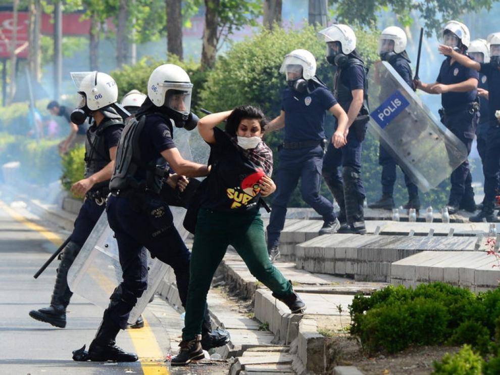 Un policía antidisturbios forcejea con una manifestante