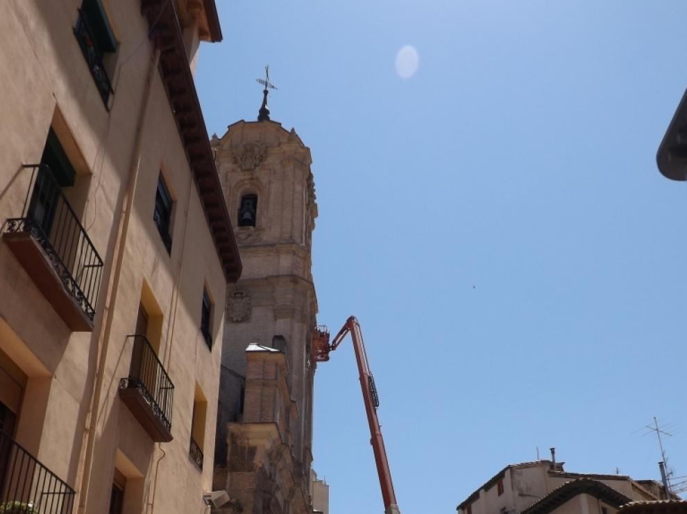 Una grúa transporta a los operarios que trabajan la fachada de la basília.