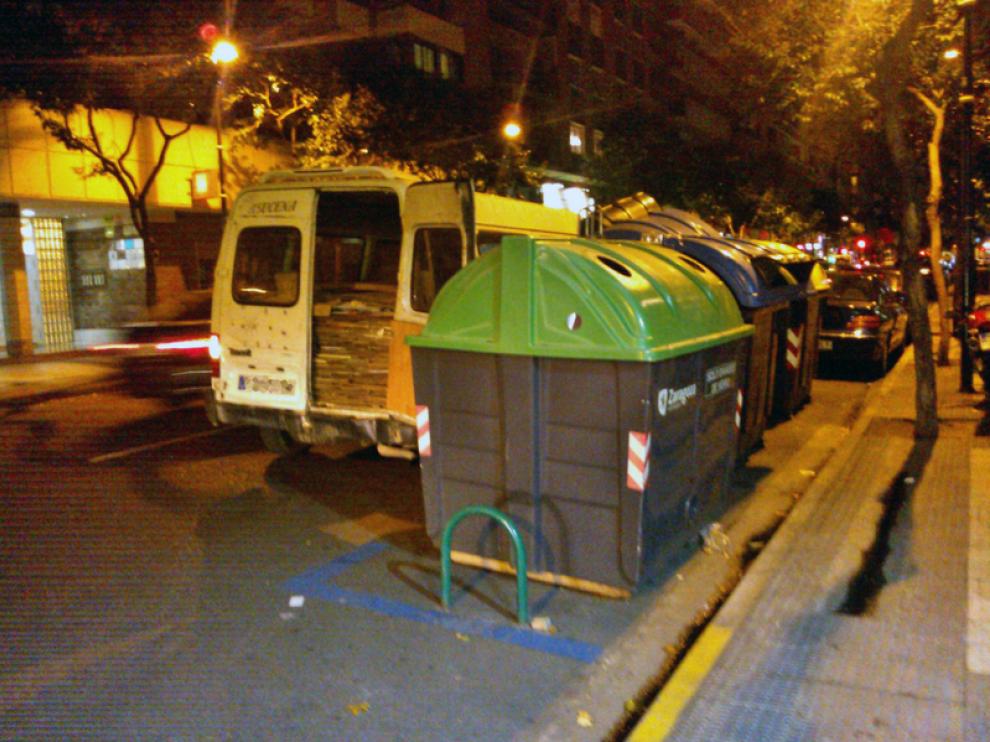 Una furgoneta llena de cartones, junto a unos contenedores