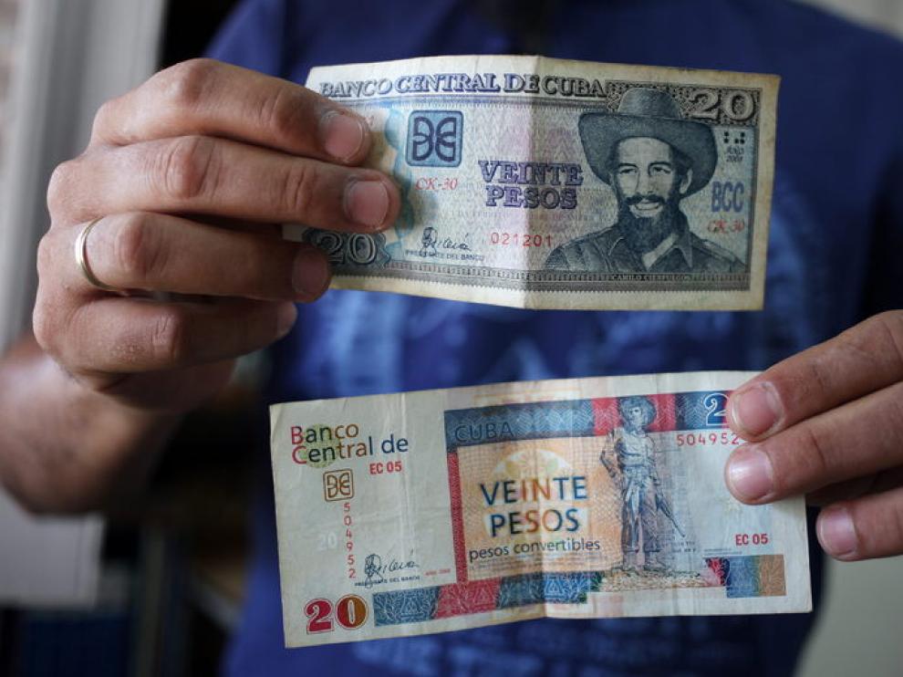 Un hombre muestra billetes cubanos de veinte pesos, uno de CUP (arriba) y otro de CUC (abajo)