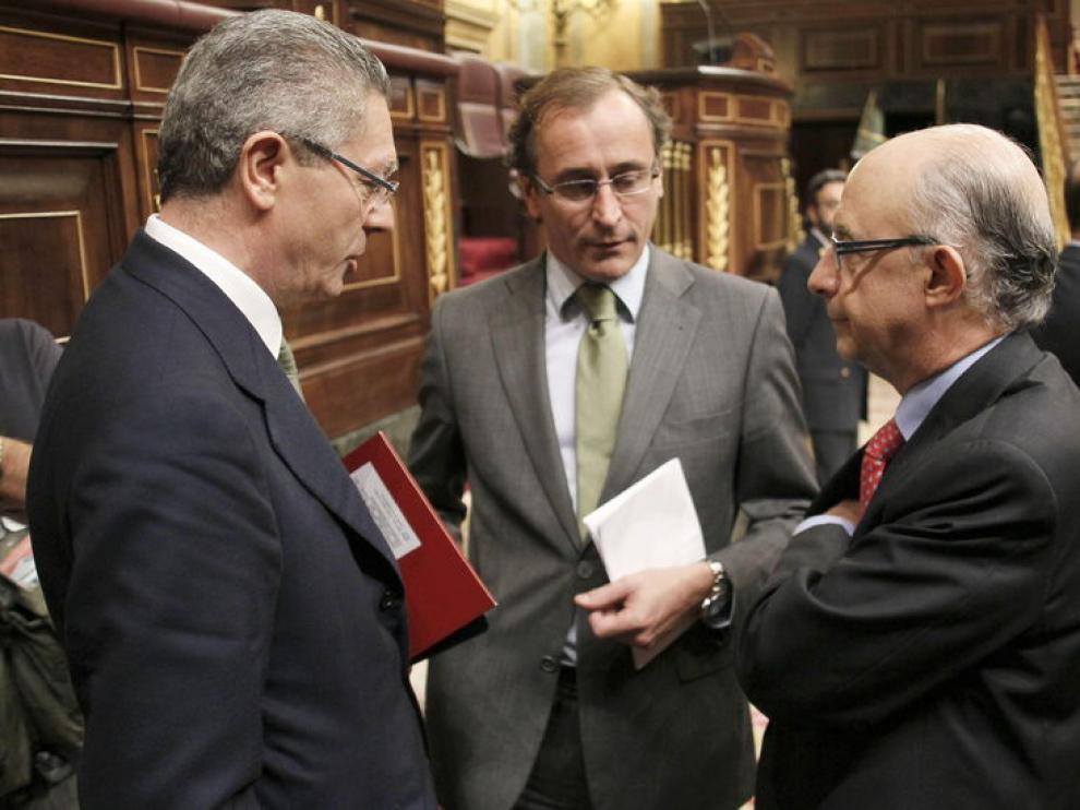 Los ministros, de Justicia, Alberto Ruiz-Gallardón (i), y de Hacienda, Cristóbal Montoro (d), y el portavoz parlamentario del PP, Alfonso Alonso