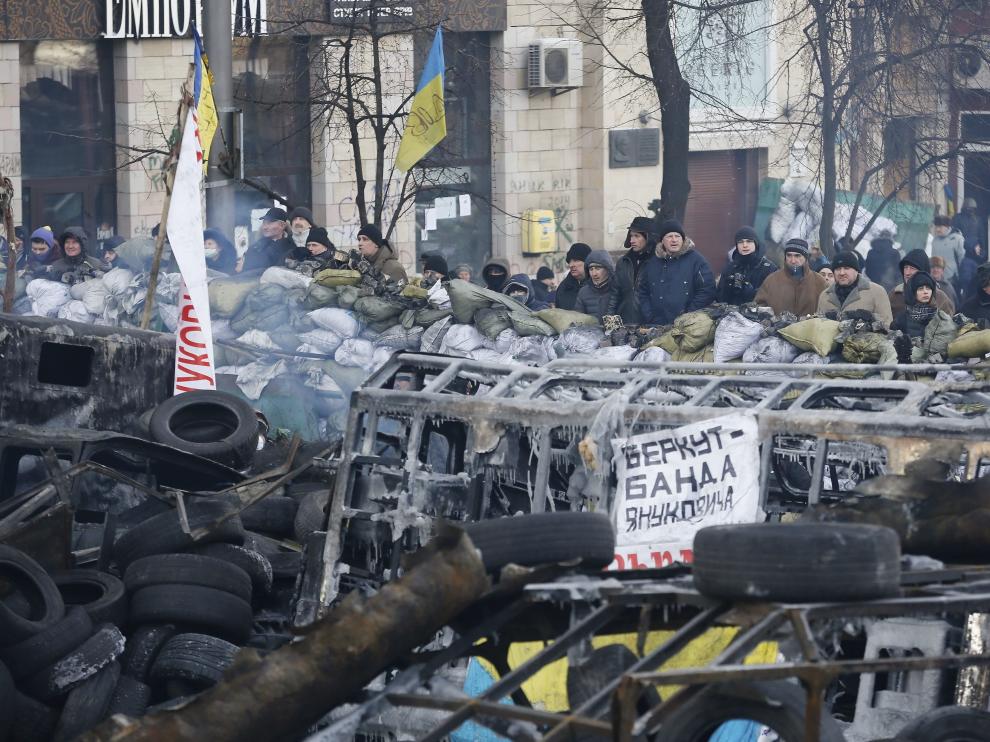 Decenas de manifestantes permanecen de pie frente a una barricada en Kiev.