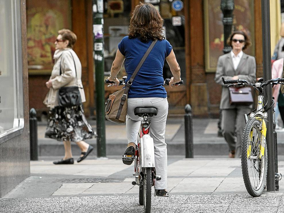 Una ciclista, circulando por la acera de la calle de San Jorge, en el Casco Histórico.