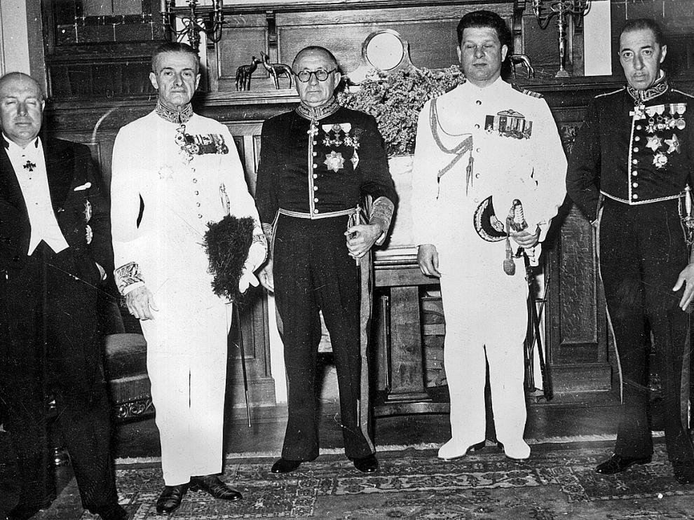 Sebastián Romero Radigales -destacado en un círculo-, con miembros del cuerpo diplomático y altos mandos militares en 1953. Debajo, pasaportes y salvoconductos como los que salvaron la vida a muchos judíos sefarditas.
