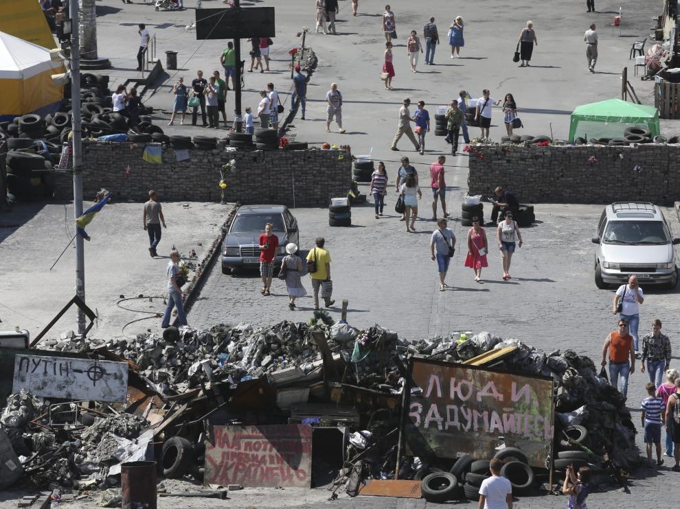 Varias personas caminan junto a las barricadas colocadas en Kiev, otras de las zonas de conflicto