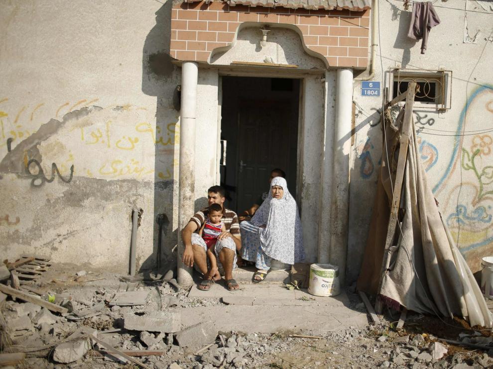 Una familia palestina, en la puerta de su casa dañada por los bombardeos