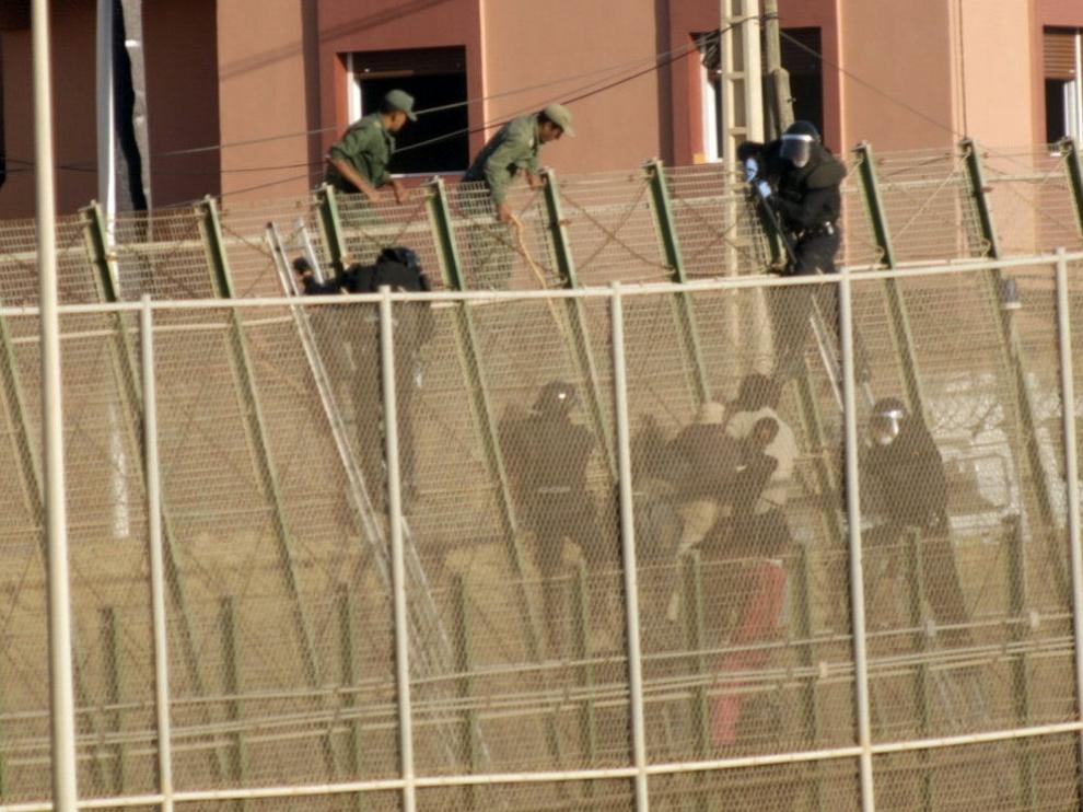 Algunos inmigrantes encaramados en las vallas fronterizas.