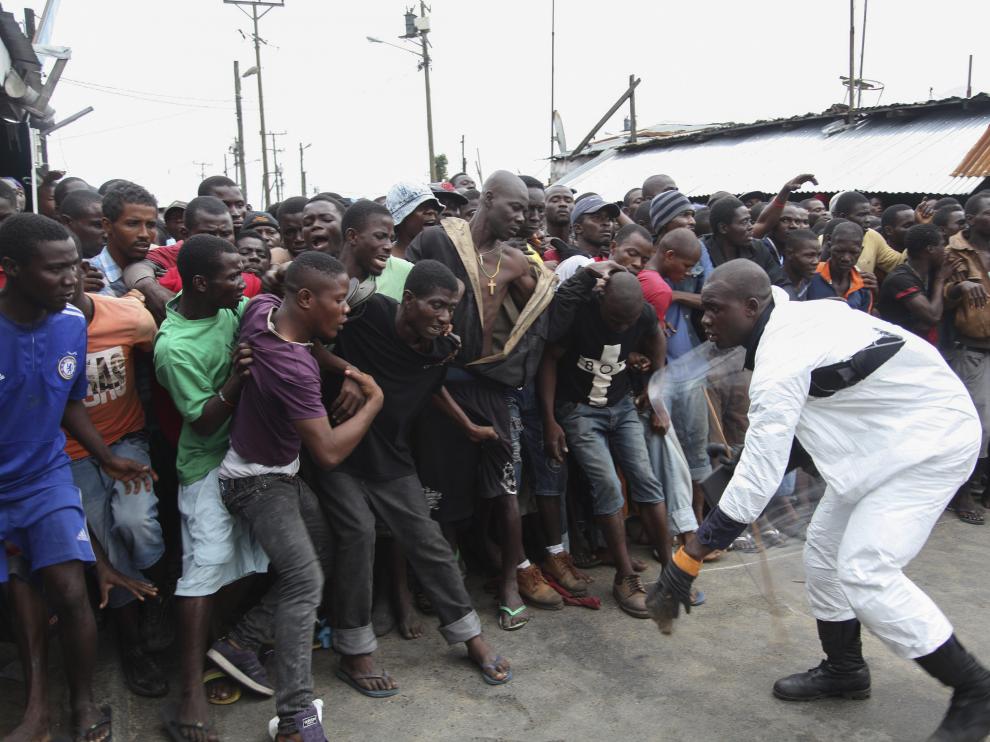 Un policía controla a los residentes en la zona de cuarentena por ébola en Liberia