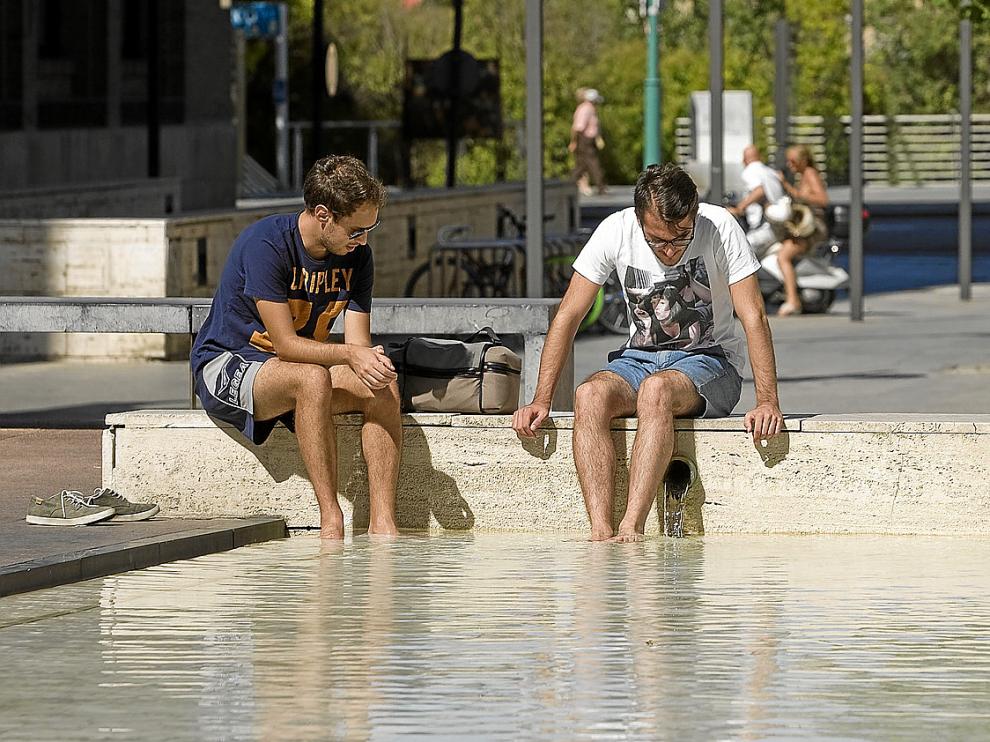 Dos ciudadanos refrescándose ayer en una fuente junto al paseo de Echegaray de Zaragoza.