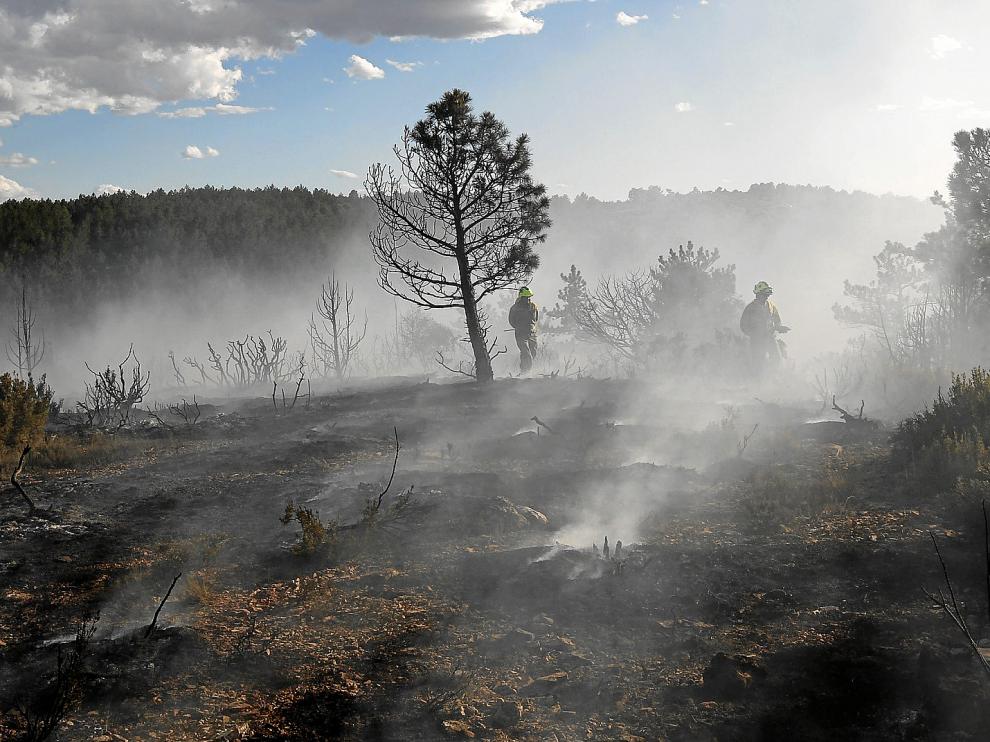 Integrantes de las brigadas contra incendios apagan los rescoldos del fuego registrado ayer por la tarde en Villel.
