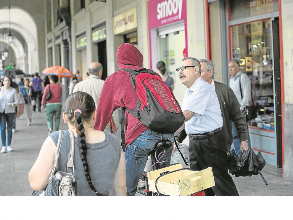 Dos peatones recriminan a un ciclista que estuviera circulando por los porches del paseo de la Independencia, ayer por la mañana.