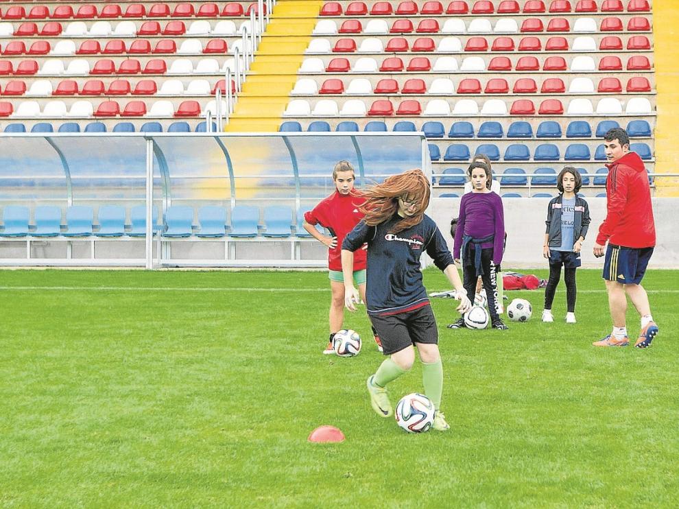 Una chica practica la conducción del balón en la jornada de puertas abiertas de la escuela de fútbol.