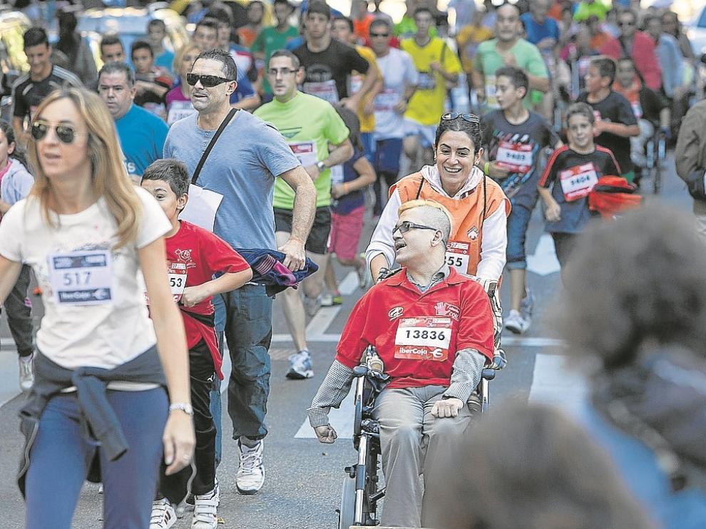 Una corredora empuja a un participante en silla de ruedas durante la pasada edición.