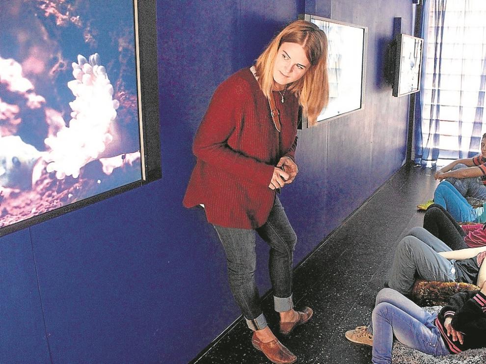 La guía Gloria Fernández, con varios niños en la sala de vídeos del Museo Móvil.