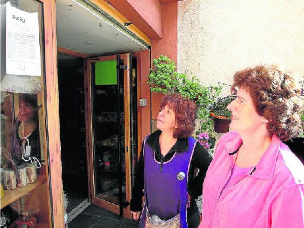 Dos vecinas de Santa Eulalia leen el bando que informa de la prohibición de beber del grifo.