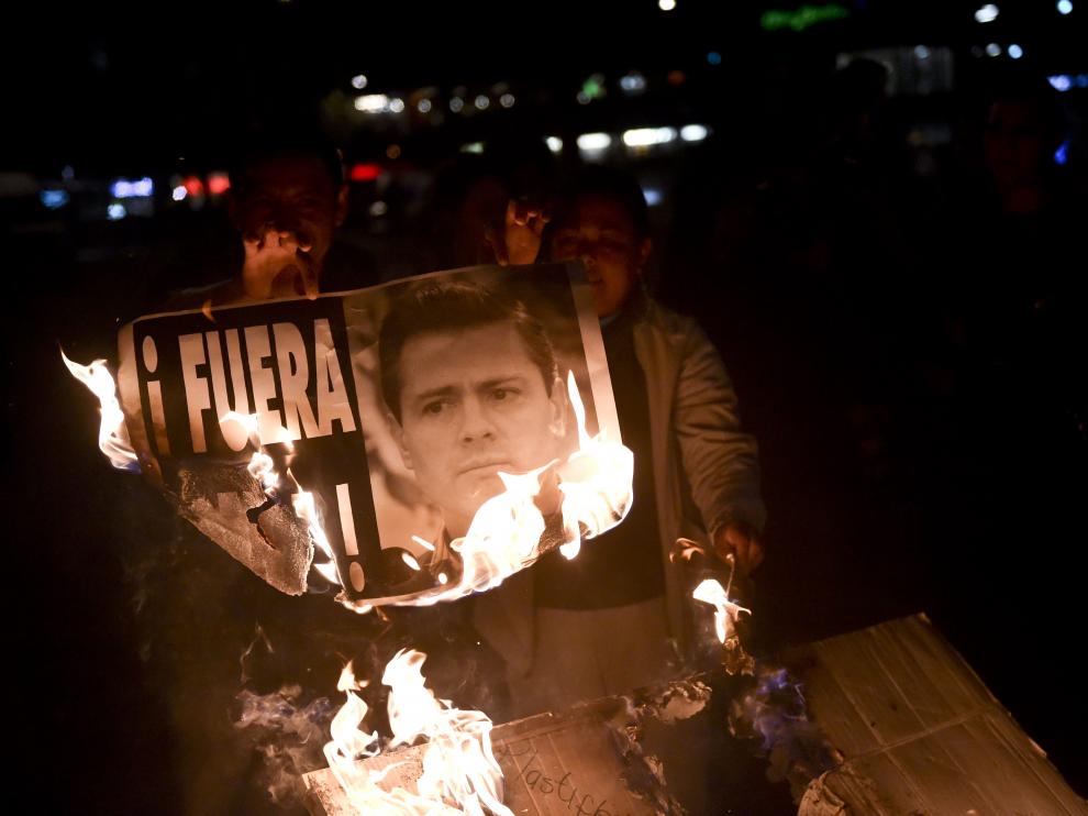 Dos manifestantes queman una imagen del presidente Peña Nieto