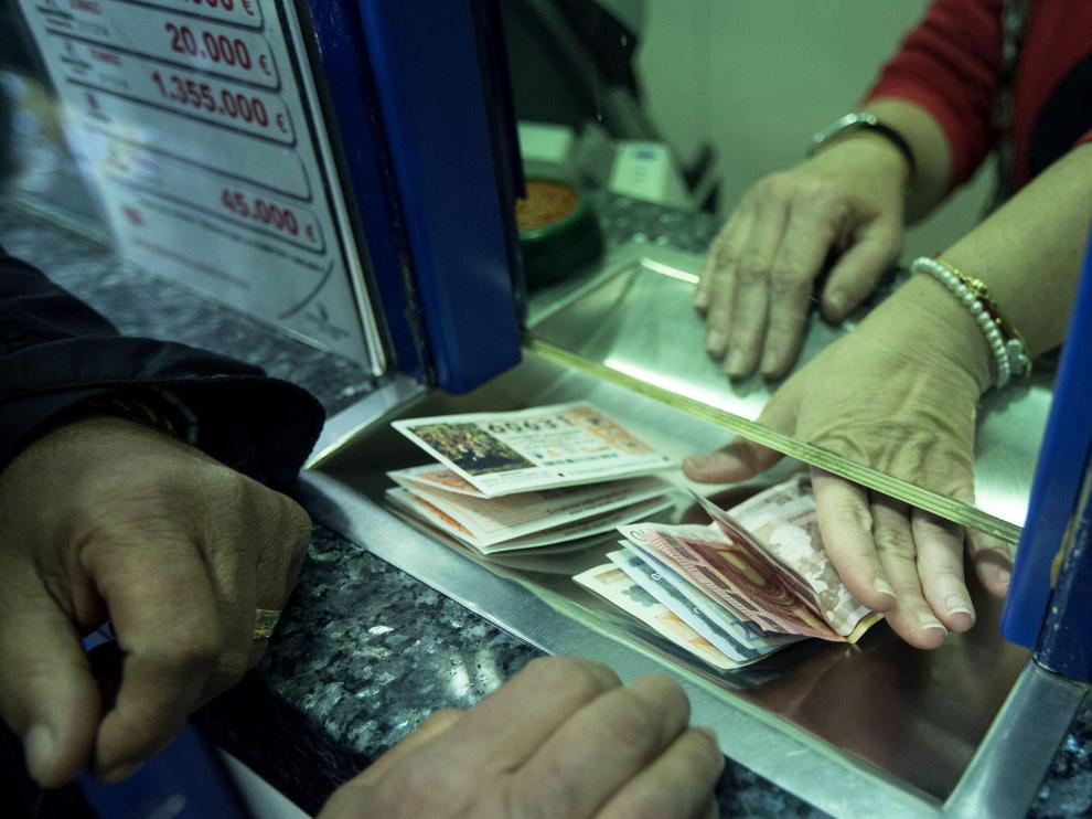 Un hombre compra varios décimos en una administración de lotería