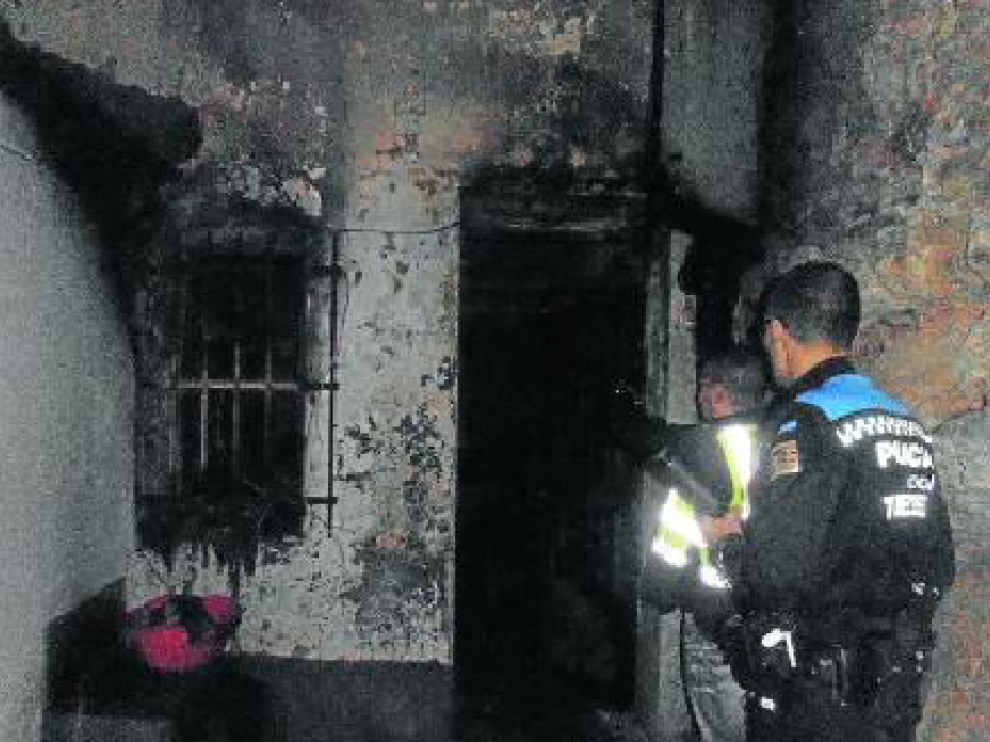 Dos policías locales revisan la casa tras el incendio