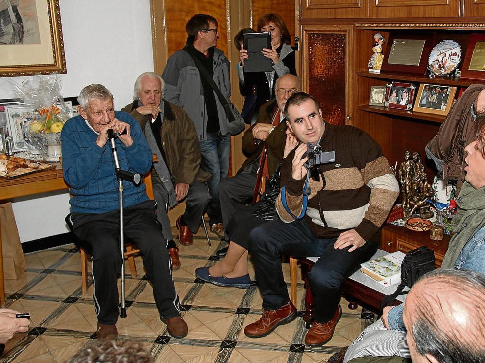 José Iranzo, a la izquierda, escucha atentamente en el salón de su casa al cantador Nacho del Río dedicándole una jota.