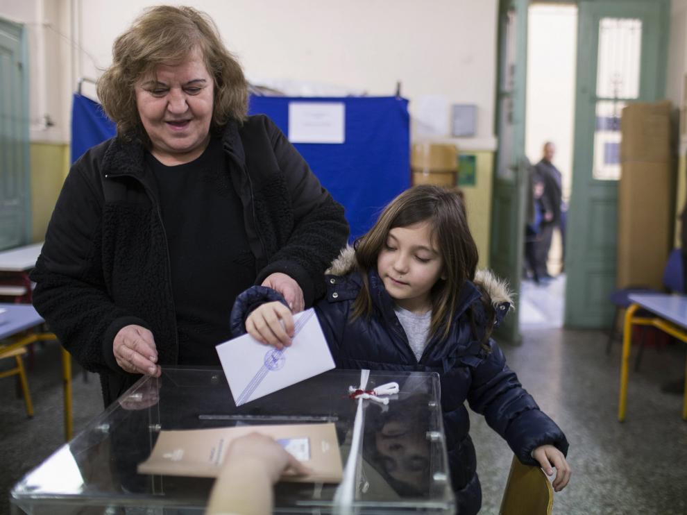 Una griega con su hija deposita su voto a primera hora de la mañana en un colegio electoral de Atenas, este domingo, 25 de enero