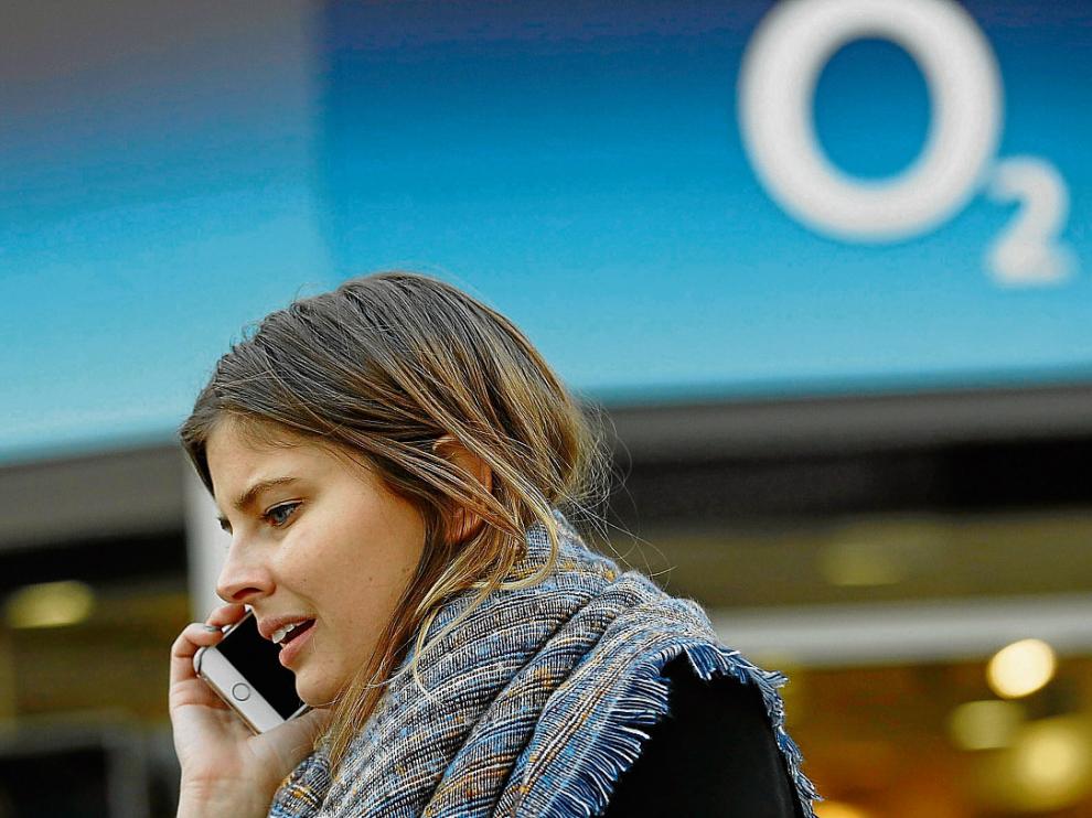 Una mujer habla por el móvil junto a la sede de una tienda de O2 en Londres.