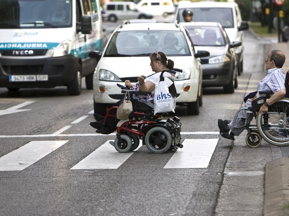 Dos zaragozanos atraviesan un cruce en silla de ruedas