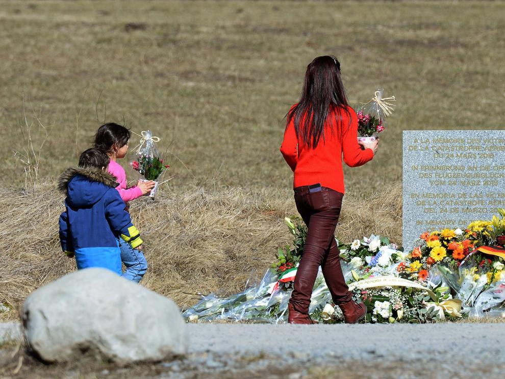 Una mujer y dos niños llevan flores a las víctimas