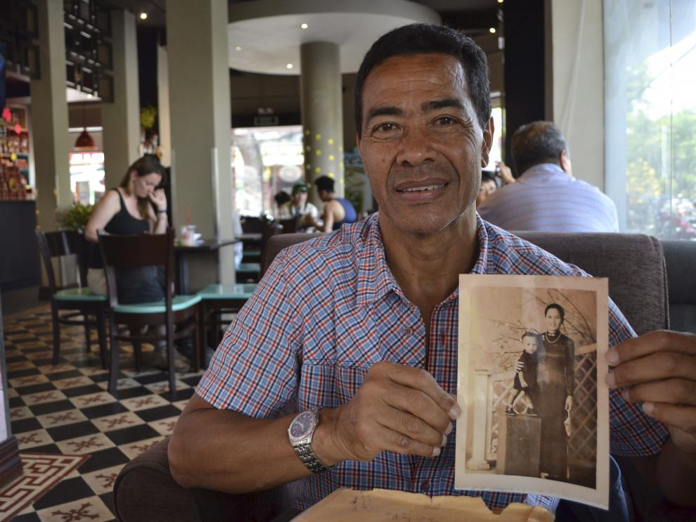 René Fairn, de 66 años, de padre militar francés y madre vietnamita, muestra una fotografía suya junto a su madre en Vietnam.