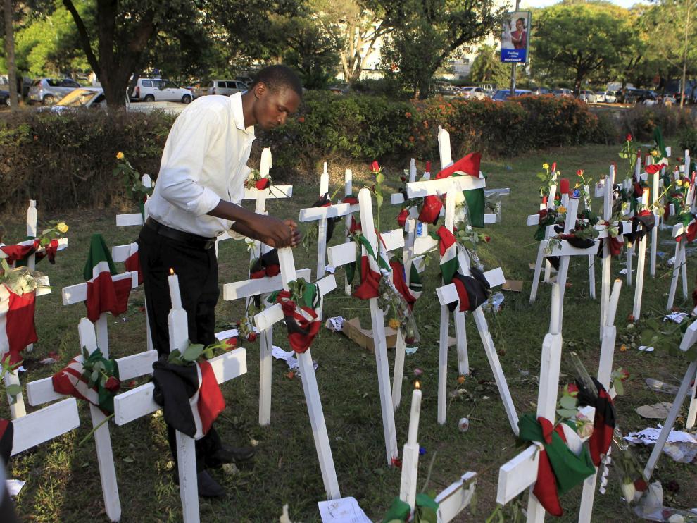 Un hombre enciende una vela cerca de cruces de madera en la esquina de Libertad en Nairobi.