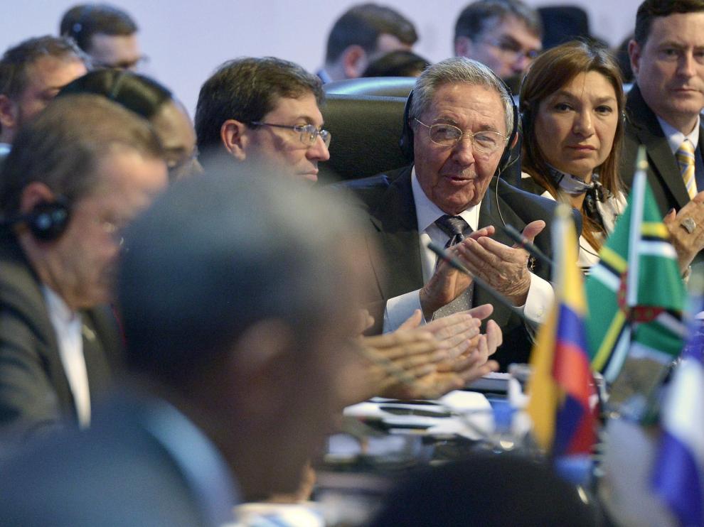 Obama en primer plano, desenfocado, con Raúl Castro aplaudiendo detrás