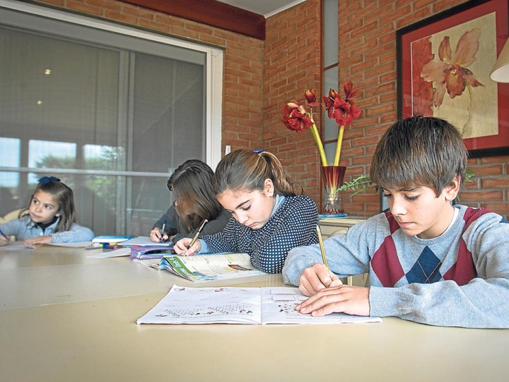 Niños de diferentes edades haciendo deberes en su casa.