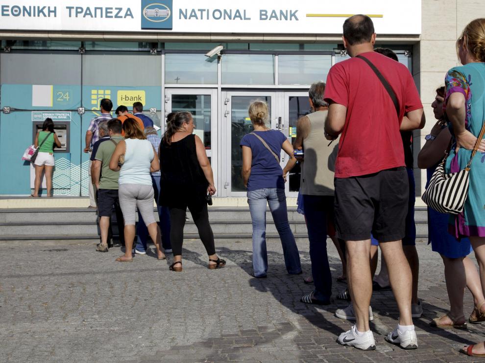 Varias personas haciendo cola para sacar dinero en un cajero en Grecia.