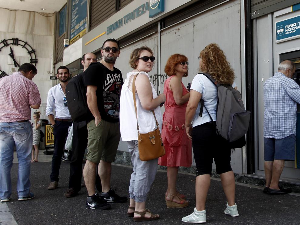 Atenienses hacen cola para retirar dinero en una sucursal del Banco Nacional de Grecia.