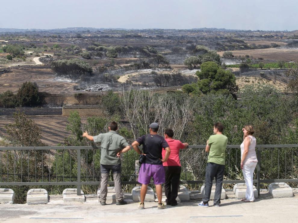 Varios vecinos mirando la superficie quemada en el incendio