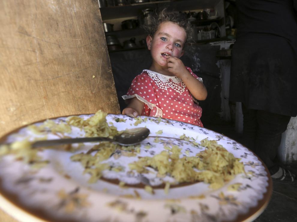 Una niña palestina muestra su plato de comida en la tienda de campaña familiar, en Susia.