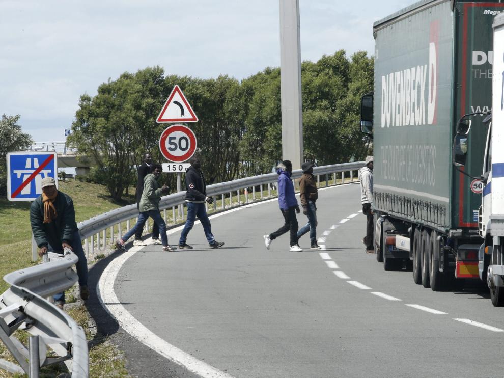 Inmigrantes cruzando la carretera cercana al Eurotúnel.