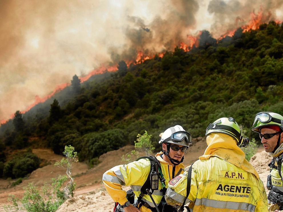 Tres agentes de protección de la naturaleza (APN) del Gobierno de Aragón comentan el avance del fuego en una zona situada entre Luna y Orés.